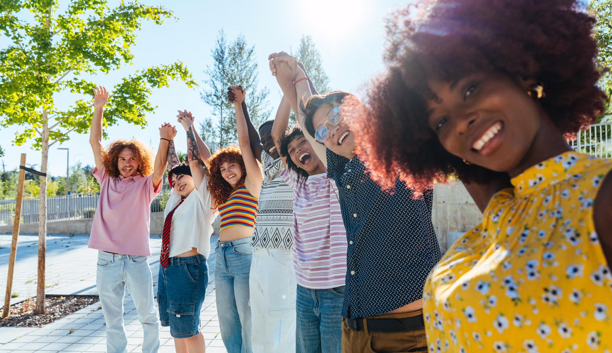 Young people raising their arms together outdoors